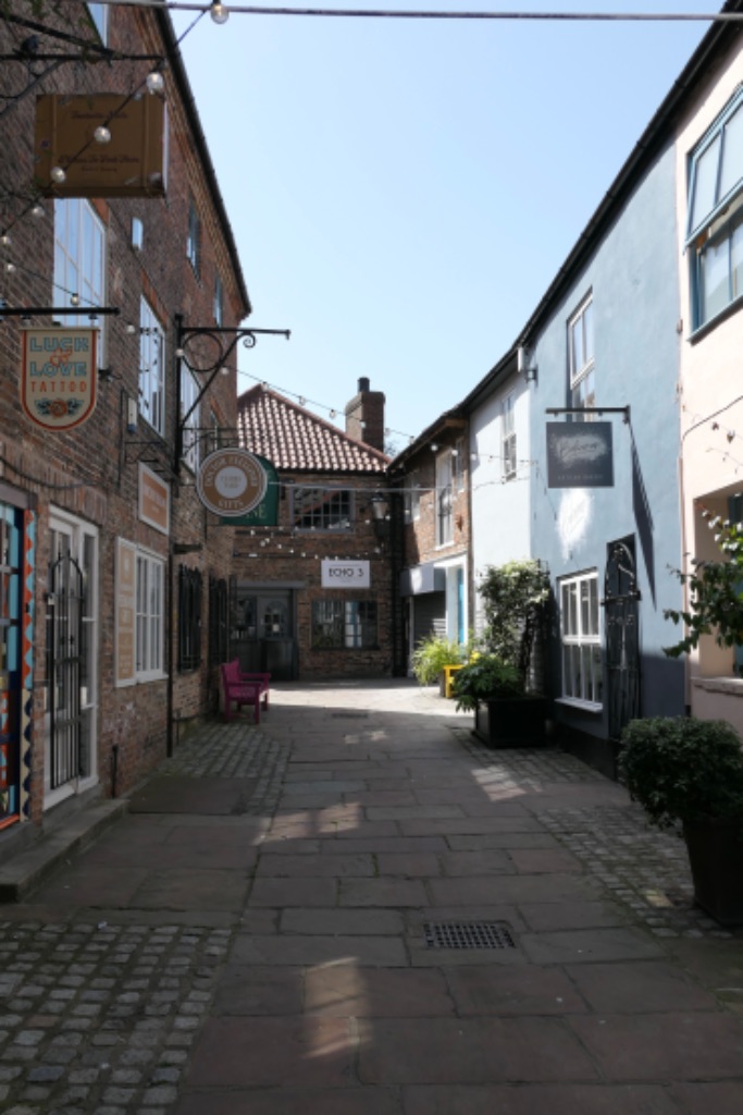 Clarks Yard, Darlington — a narrow cobbled alleyway lined with independent businesses, hanging signs and string lights
